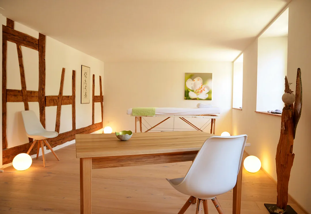 Heller Praxisraum mit Liege, Tisch und Leuchtkugeln
